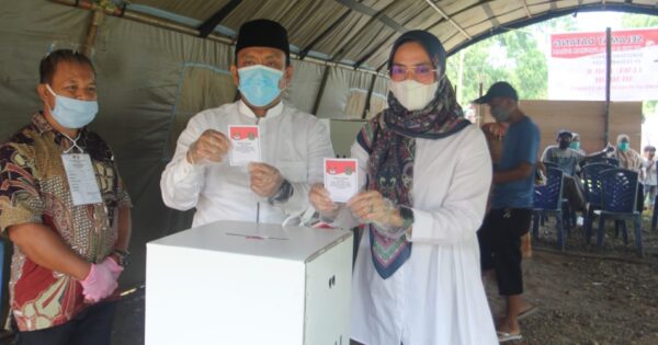 Irwan Bachri Syam didampingi istrinya, Ani Nurbani menggunakan hak pilihnya di TPS 8, Desa Puncak Indah, Kecamatan Malili, Rabu (09/12/2020) pagi. foto:input rakyat