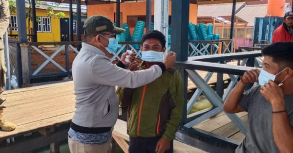 Plt Camat Towuti, Sainal memasangkan masker kepada warga yang ditemui di Desa Timampu, Minggu (15/8/2021). Foto: Erik/teraskata.com
