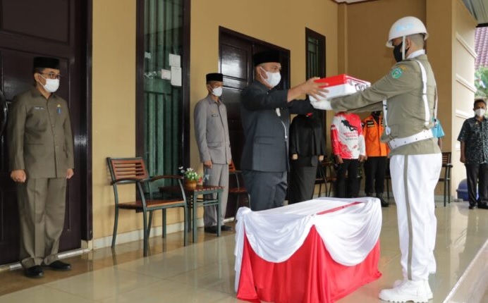 Bupati Luwu Timur, Budiman menyerahkan bendera Merah Putih untuk dibentangkan di bawah laut, Minggu (15/8/2021), dalam rangka perayaan HUT Kemerdekaan RI ke-76. Foto: HumasPemkabLutim