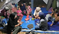 Warga pengungsi banjir Kabupaten Bireuen, Aceh, berkumpul di dalam tenda di halaman Kantor Bupati Bireuen, duduk berdesakan di atas terpal saat malam hari.