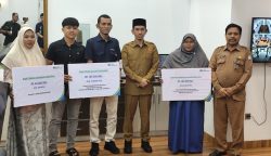 Bupati Aceh Barat Tarmizi S.P, M.M Didampingi Kepala BPJS Ketenagakerjaan Cabang Meulaboh Memberikan Secara Simbolis Kepada Ahli Wars Penerima Manfaat Santunan Kematian Dan Beasiswa. [Foto :Ist]